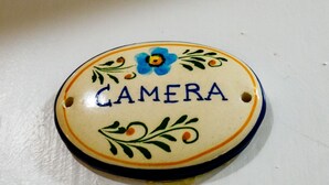A ceramic plate with the word "CAMERA" and decorative elements.
