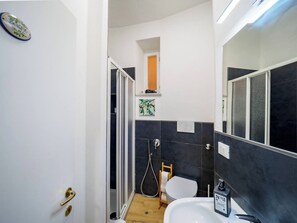 A compact bathroom with a shower, toilet, and sink.