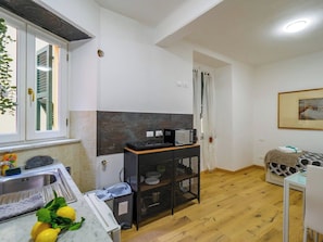 A compact kitchen with a sink, a microwave, and a small cabinet.