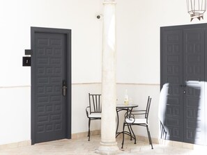 A room with a dark door, a white pillar, a small round table with two chairs, and a bottle of alcohol. - Elegant and comfortable open-plan studio with Free Parking (Sevilla)