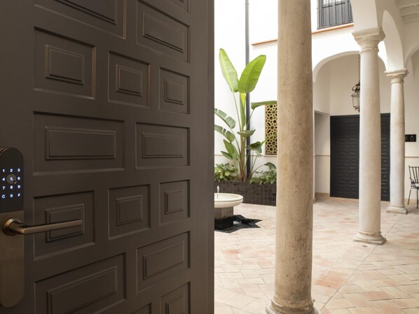 A modern interior with a keypad door, a tiled courtyard, and a columned area.