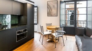 Een moderne keuken met een eethoek, met een houten tafel en stoelen, een bank en een groot raam met uitzicht.