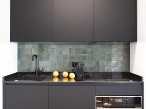 Una cocina moderna con encimera negra, un lavabo y una estufa.