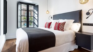 Un dormitorio moderno con una cama grande, una mesita de noche, una lámpara colgante y una ventana con vistas al exterior.