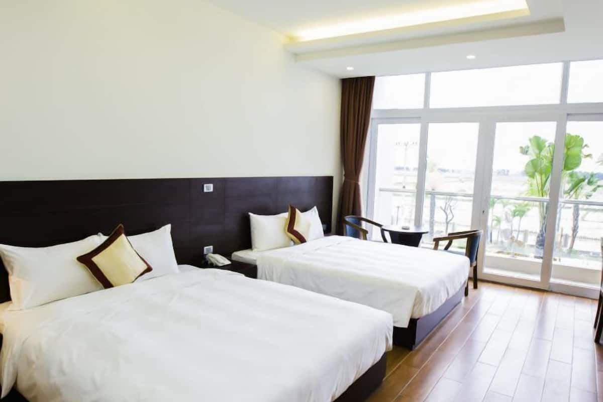 A hotel room with two beds, a large window with a view, and a modern ceiling design.