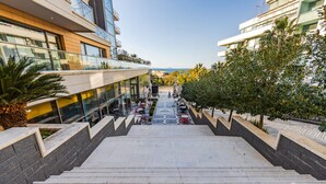 Un escalier menant à un bâtiment doté d’une terrasse et offrant une vue sur la mer.