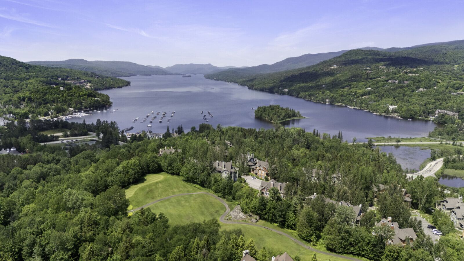 Ein Anwesen am Seeufer mit Golfplatz, mehreren Häusern und Booten auf dem Wasser.
