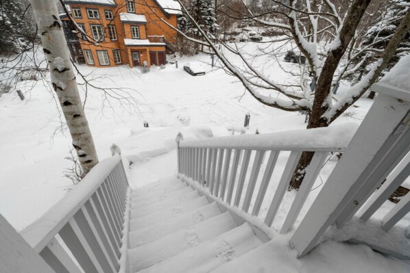 A snow-covered staircase leading to a building with a red facade.