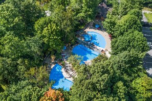 An aerial view of a resort with multiple swimming pools surrounded by dense greenery.