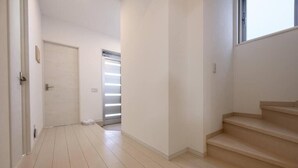 Um corredor com uma porta, uma escada e uma janela.