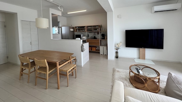Uma sala de estar moderna com área de jantar, cozinha e televisão de tela plana na parede.