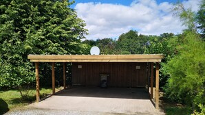 A covered outdoor area with a gravel floor, wooden beams, and a satellite dish on the roof. - Vacation apartment in the countryside between Binz and Sellin (Zirkow)