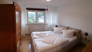 A bedroom with a bed, a window, a radiator, and a nightstand with a lamp. - Vacation apartment in the countryside between Binz and Sellin (Zirkow)
