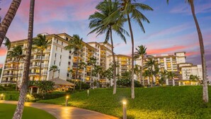 A multi-story hotel with a central courtyard surrounded by palm trees and a well-lit pathway. - Hale Pikake O-406 Comfort and Joy in one place (Kapolei)