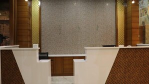 A reception area with a checkered floor pattern, a central partition, and a patterned wall. - Hotel Manglam (Pachpadra)