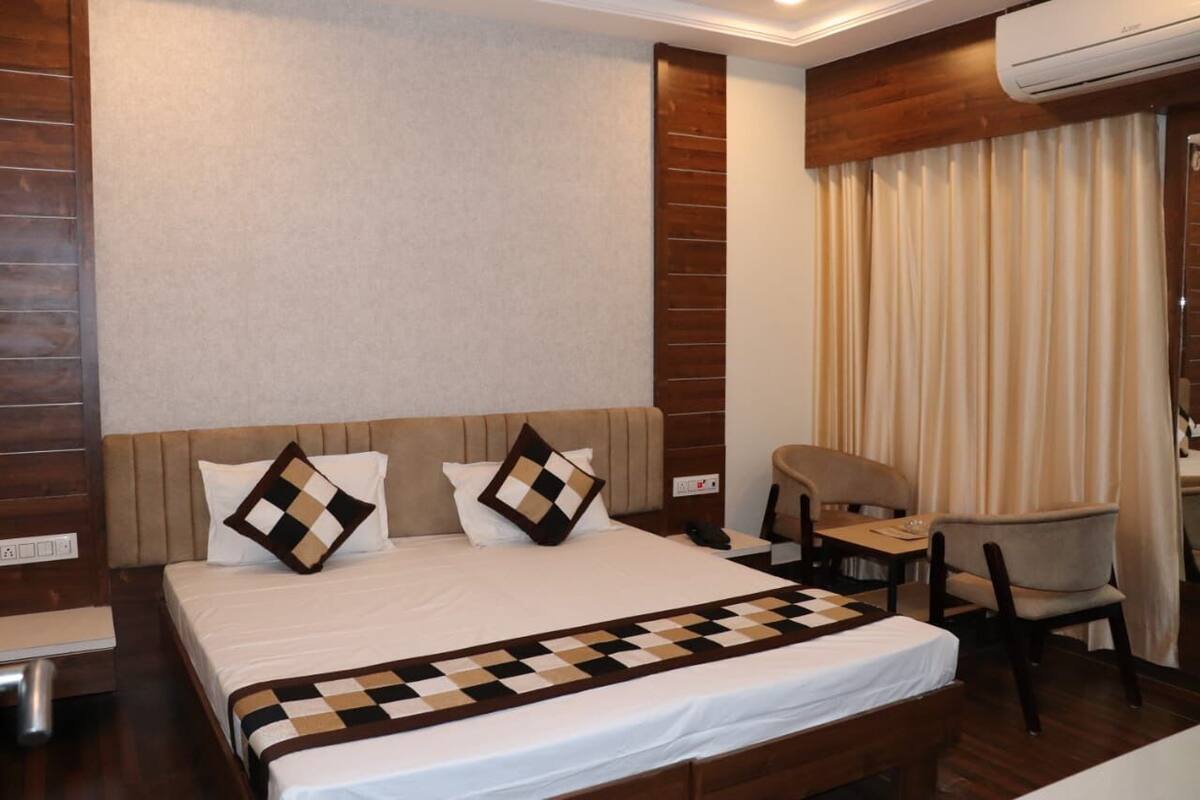 Quarto de hotel com uma cama grande, uma escrivaninha e uma cadeira.