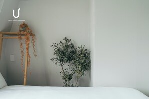 Habitación de hotel con cama, escalera de madera y planta en la pared.