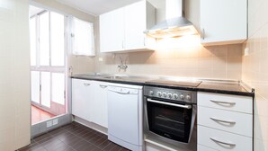 Eine Küche mit weißen Schränken, einem Geschirrspüler, einem Backofen und einem Fenster.