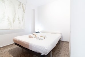 Una camera d'albergo moderna e pulita, con un letto, un comodino e un'opera d'arte appesa al muro.