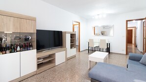 Ein modernes Wohnzimmer mit Fernseher, Unterhaltungseinheit und Sitzgelegenheit.