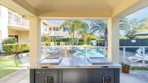 Un espace aménagé au bord de la piscine, comprenant une piscine, des chaises longues et une vue sur un bâtiment en arrière-plan.