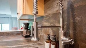 Una cocina con grifos de acero inoxidable, una encimera de madera y dos botellas marrones sobre la encimera.