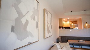 Una sala de estar moderna con un sofá gris, un banco de madera y arte abstracto en la pared.