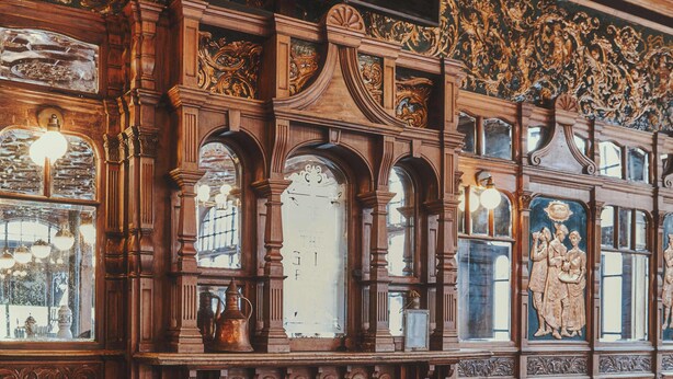 Una habitación con chimenea de ladrillo, muebles de madera y decoraciones murales elaboradas.