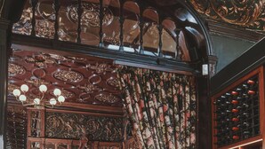 Un interior con pisos de madera, una cortina floral y una estantería para vinos.