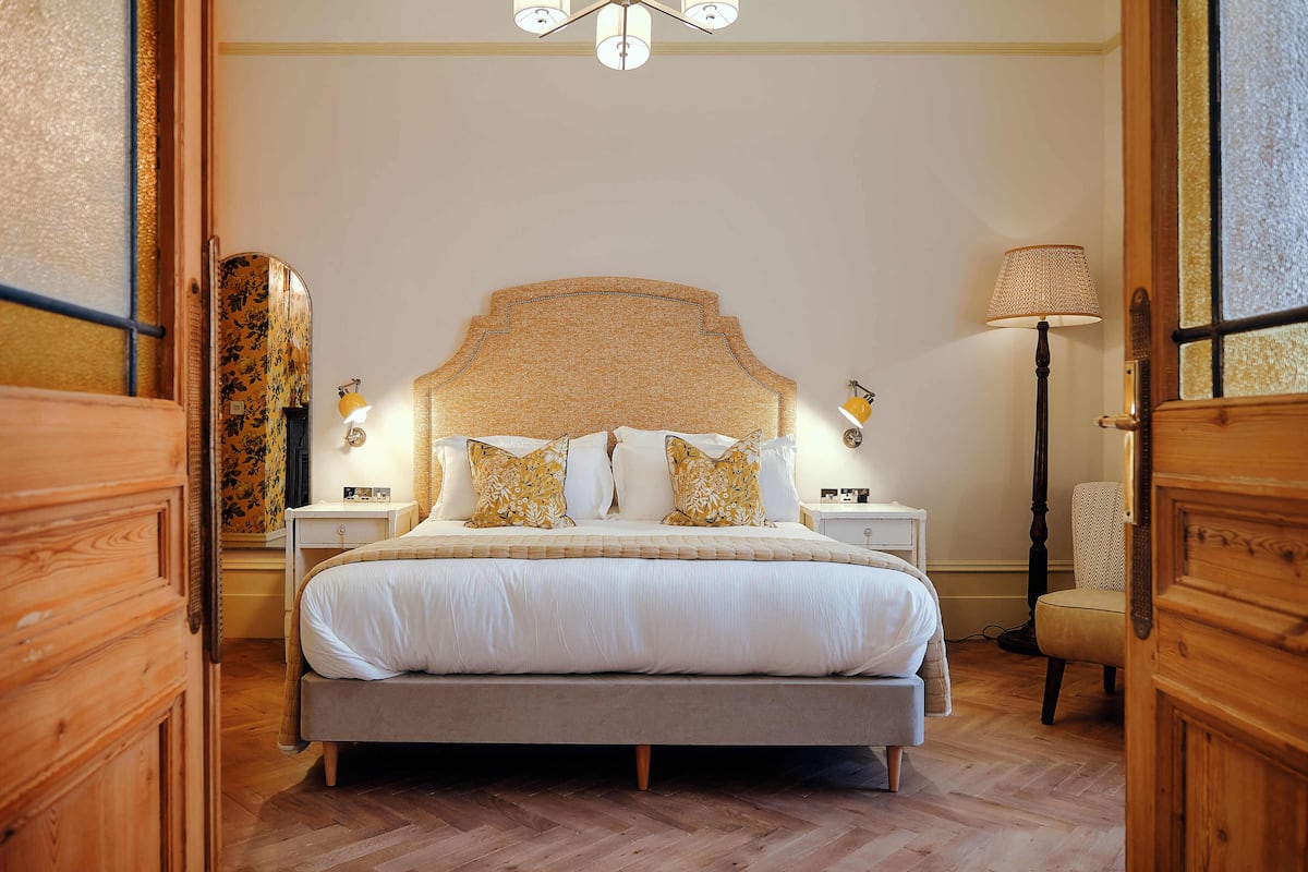 Quarto bem arrumado com cama grande, abajures e candeeiro de chão.