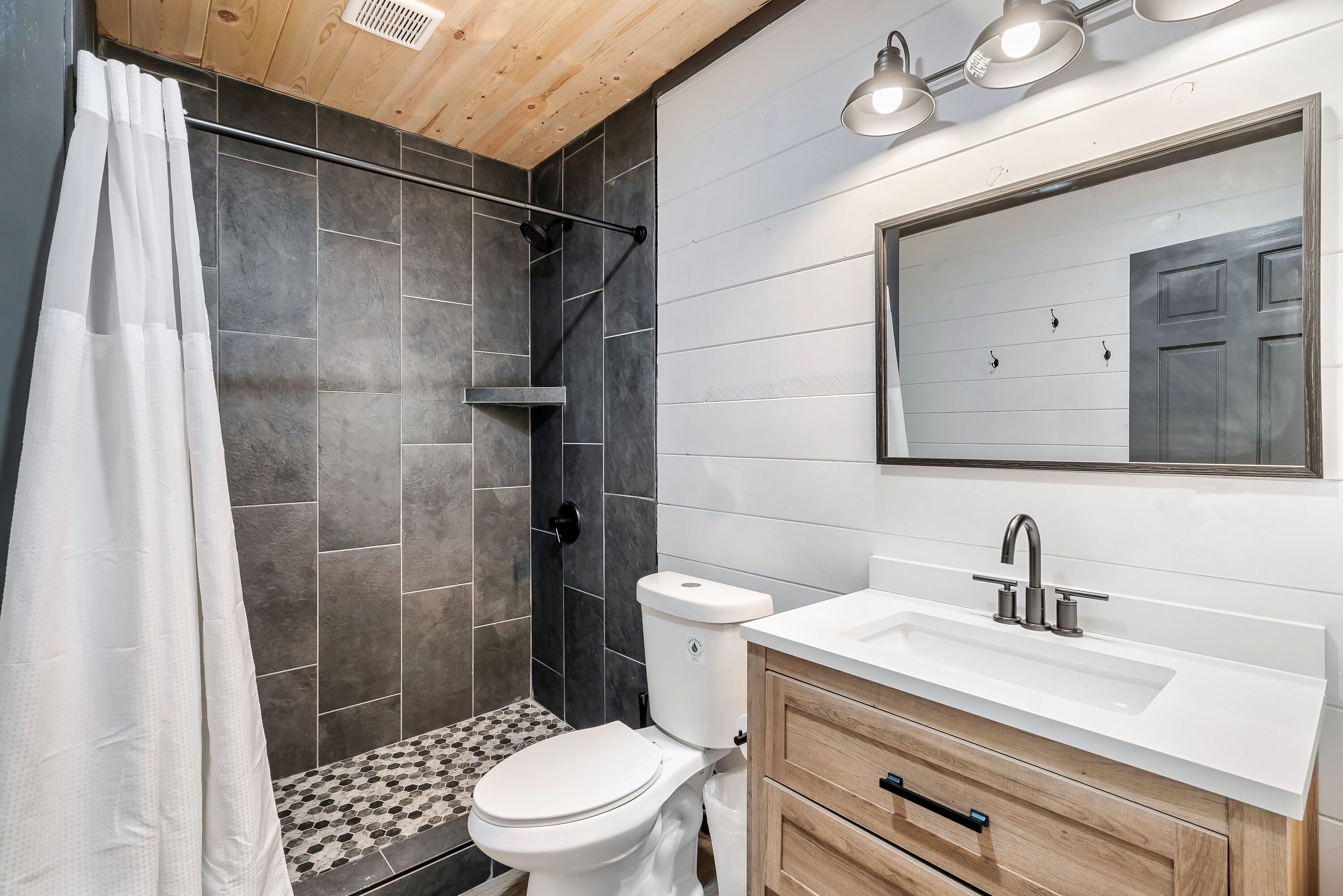 Une salle de bain moderne équipée d’une douche, de toilettes, d’un lavabo et d’un meuble-lavabo.