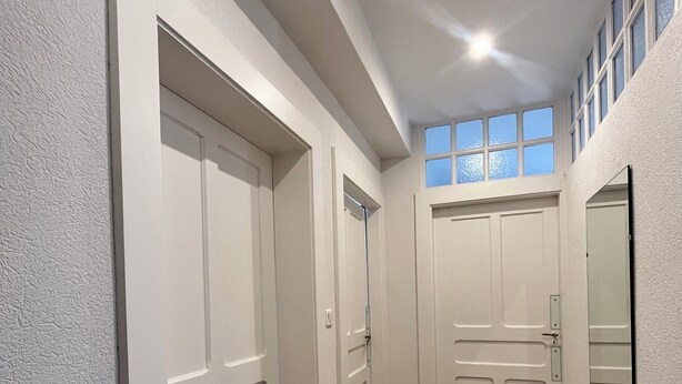 A hallway with white doors, wooden flooring, and a window with multiple panes. - N°9, in the heart of the Haut Doubs tourist region, 10 minutes from Switzerland (Damprichard)