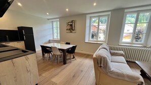 A modern kitchen with a dining table and chairs, a sofa, and large windows with a view of greenery. - N°9, in the heart of the Haut Doubs tourist region, 10 minutes from Switzerland (Damprichard)