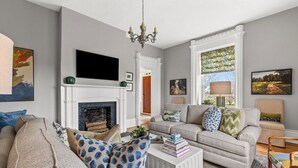A living room with a fireplace, a sofa set, a coffee table, and artwork on the walls.