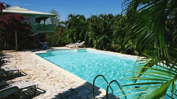 A swimming pool with lounge chairs and a stone-tiled deck.