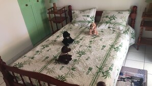 A bed with a bamboo-patterned bedspread, two pillows, and a stuffed dog toy.