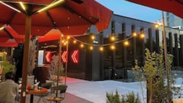 An outdoor seating area with red umbrellas, wooden tables, and string lights. - Piso, Apartamento, Centro de Madrid (Madrid)