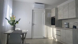 Une cuisine moderne équipée d’un four encastré, d’une machine à café et d’une plante en pot posée sur le rebord de la fenêtre.