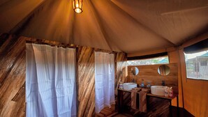 A tent-style bathroom with wooden walls, a sink, and a mirror. - Moyo Tented Camp (Serengeti)