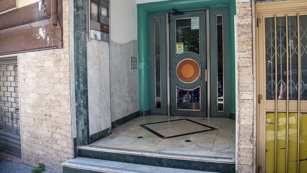 A building entrance with a green door, a number 12 sign, and a metal gate. - A Casa Di Marco (Salerno)