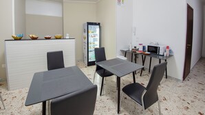 A small, modern kitchenette with a refrigerator, microwave, and a small table with chairs. - A Casa Di Marco (Salerno)