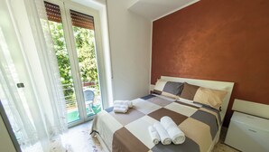 A bedroom with a checkered bedspread, a white headboard, and a sliding glass door leading to a balcony. - A Casa Di Marco (Salerno)