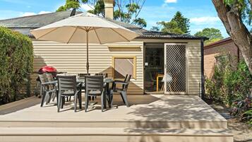 A patio with a table and chairs, a barbecue grill, and a covered umbrella.
