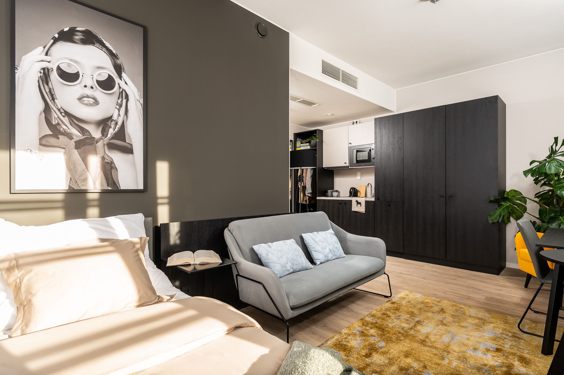 Uma sala de estar moderna com um sofá cinza, uma mesa pequena com um livro e um quadro grande na parede.