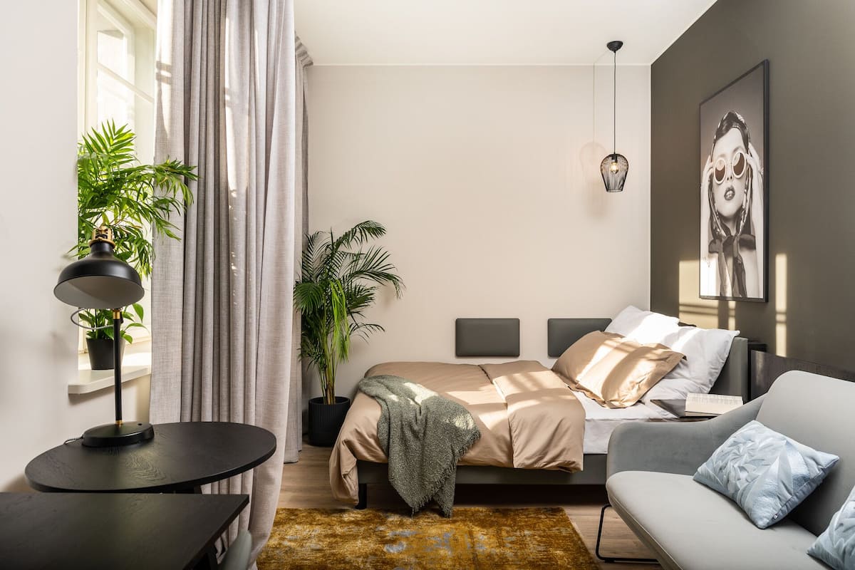 Ein modernes Schlafzimmer mit einem Bett, einer Couch, einem Schreibtisch und einer Zimmerpflanze.