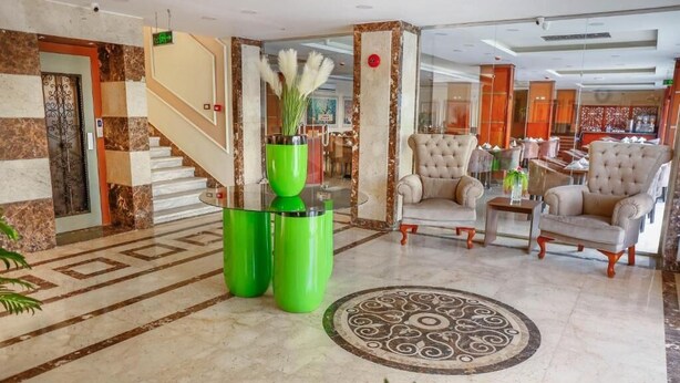 A lobby with a marble staircase, a green vase with plants, and a seating area with cushioned chairs. - The Palm Hotel Kafr El-Sheikh (Kafr el Shaikh)