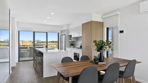 A modern kitchen with a central island, large windows, and a view of the cityscape.