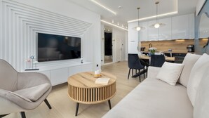 Una sala de estar moderna con televisor, sofá, sillones y una mesa de centro redonda de madera.
