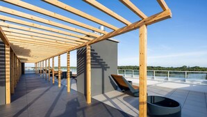 Un espacio exterior techado con una pérgola de madera, una piscina y vistas al paisaje.