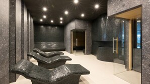 Un área de spa con zona de estar, puerta de cristal y suelo de baldosas.
